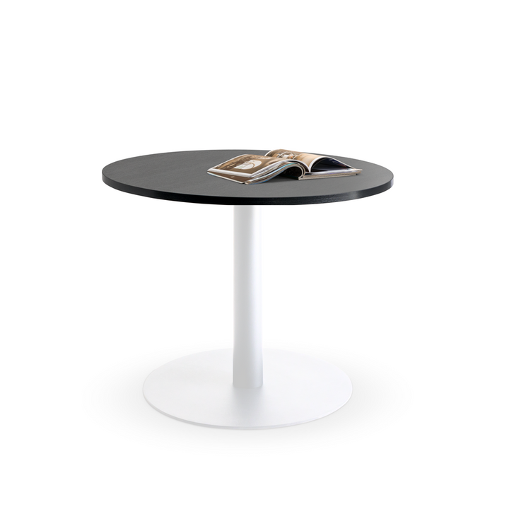 Introducing the Lunar 900 Meeting Table from Home Office Space NZ, a small yet durable table featuring a dark tabletop and a sleek white pedestal base. An open magazine with colorful pages adorns the tabletop, making it an ideal addition to any home office. The scene is set against a plain white background.