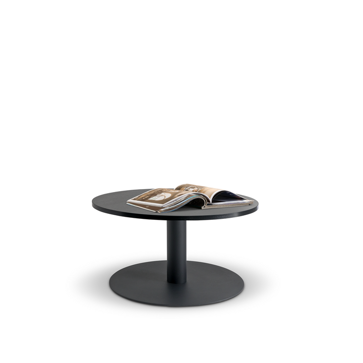 The Lunar 600 Coffee Table from Home Office Space NZ is a modern round piece with a thick pedestal base, featuring a durable melamine top. An open magazine rests on the tabletop, showcasing images and text. The white background accentuates the table's sleek design and customizable options.