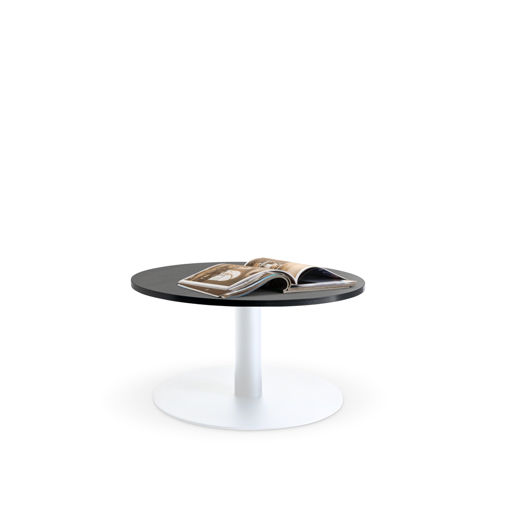 The Lunar 600 Coffee Table by Home Office Space NZ, featuring a durable melamine top, is showcased in the image. This small black round coffee table with a sleek white pedestal base has an open magazine on it, displaying photos and text. The background is plain and white, emphasizing the minimalist design of this customizable piece.