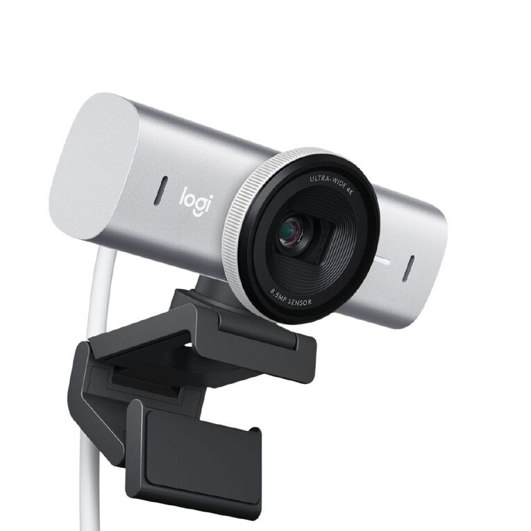 A grey Logitech MX Brio Ultra HD 4K Webcam from Home Office Space NZ with a black mounting clip, featuring an advanced STARVIS sensor. The camera boasts a wide, round lens and an "Ultra HD 4K" label. It is connected by a white cable and designed to be clipped onto a monitor or other flat surface. The Logitech logo is visible on the front.